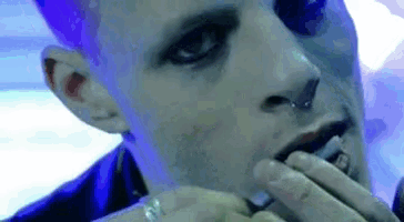 a close up of a man smoking a cigarette with a nose ring .
