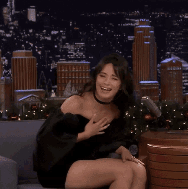 a woman wearing a choker is laughing while sitting on a couch