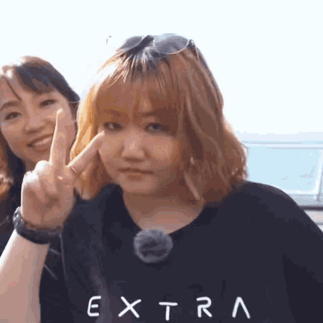 a woman wearing a black shirt that says extra giving the middle finger