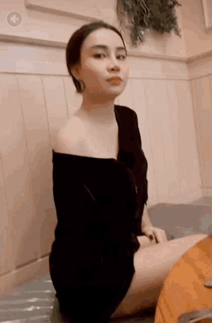 a woman in a black off the shoulder dress is sitting on a table .