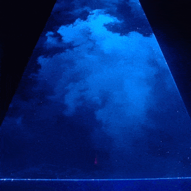 a blue pyramid with smoke coming out of it in the dark