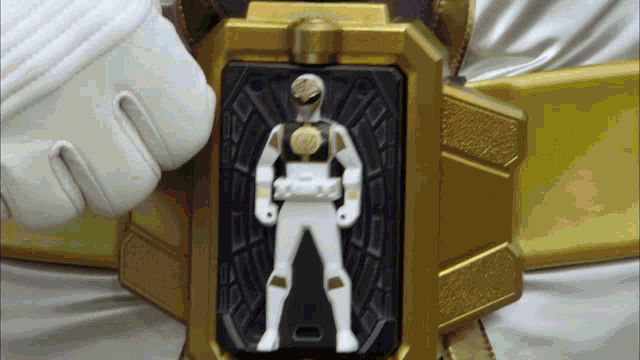 a white power ranger is standing in front of a black and gold item