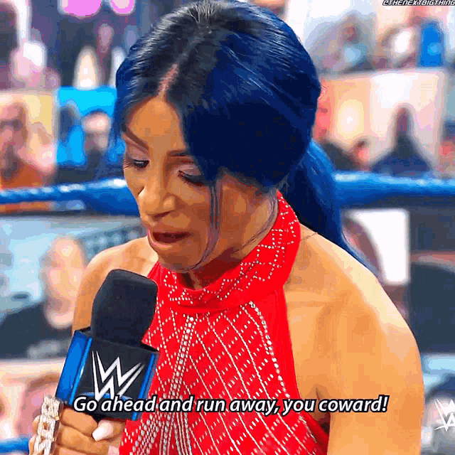 a woman in a red dress is speaking into a microphone with the words go ahead and run away you coward