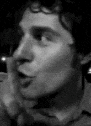 a black and white photo of a man talking on a telephone .