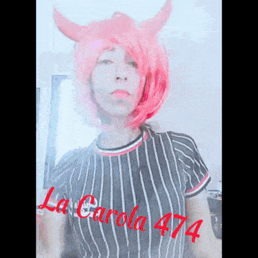 a woman with pink hair and horns is wearing a black and white striped shirt .