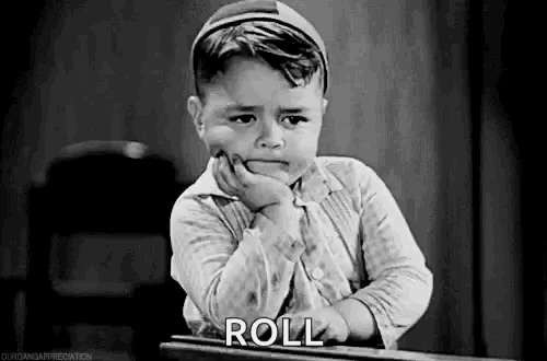 a black and white photo of a little boy sitting at a desk with his hand on his chin and the word roll .
