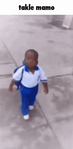 a little boy is walking down a sidewalk with a backpack on his back .