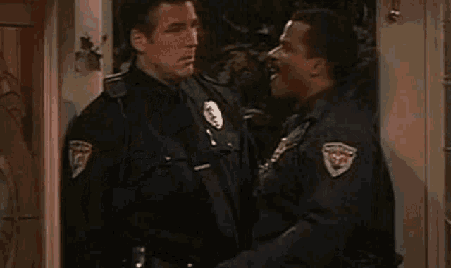 a man and a police officer are kissing in front of a door .