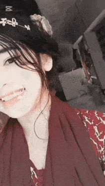 a girl wearing a red scarf and a flower headband is smiling for the camera .