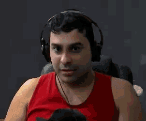a man in a red tank top is wearing headphones and making a funny face