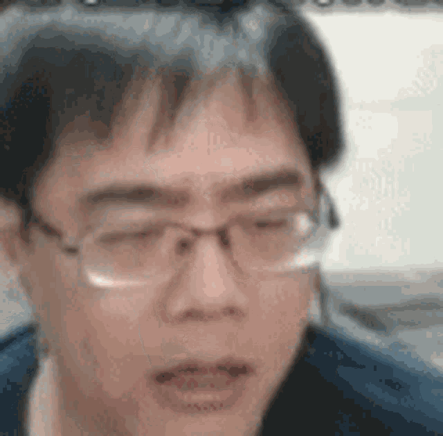 a man wearing glasses and a blue shirt is making a funny face .