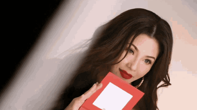 a woman with red lipstick is holding a red card