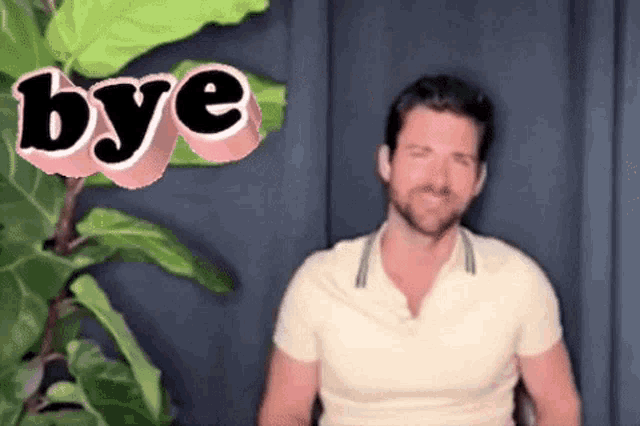 a man in a white shirt is sitting in front of a plant and the word bye is coming out of his mouth .