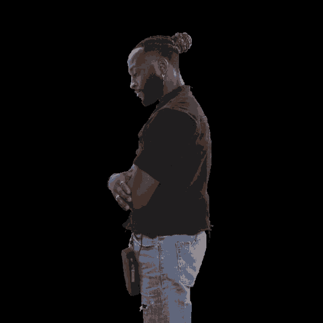 a man wearing a black shirt and blue jeans giving a thumbs up