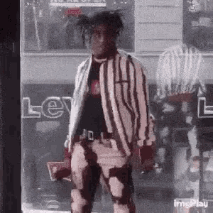 a man in a striped jacket and pants is standing in front of a window .