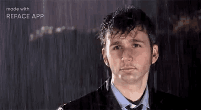 a man in a suit and tie is standing in the rain with his eyes closed .