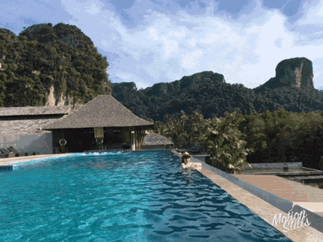 a person is swimming in a pool with mountains in the background and the words motion stills on the bottom