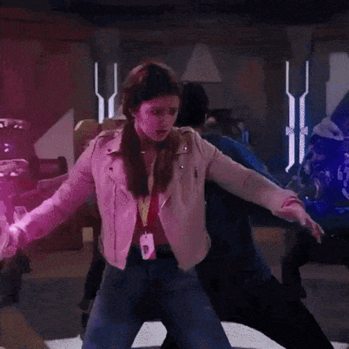 a woman in a white jacket is standing in a room holding a purple object .