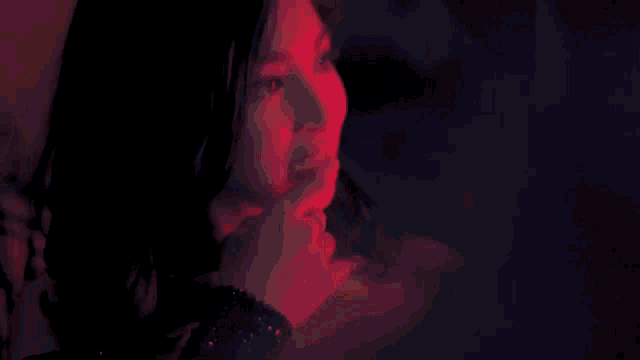 a woman is covering her mouth with her hand in a dark room .