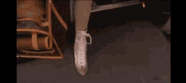 a woman wearing pink shoes is standing next to a car with a purse .