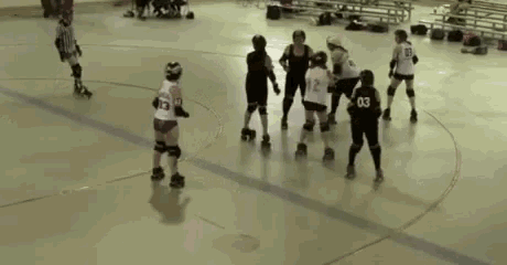 a group of roller derby players are playing a game on a rink and one of the players has the number 03 on her jersey