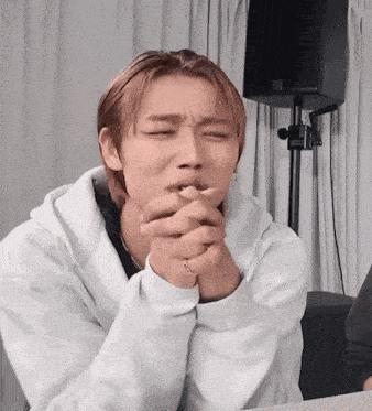 a young man in a white hoodie is making a funny face with his eyes closed