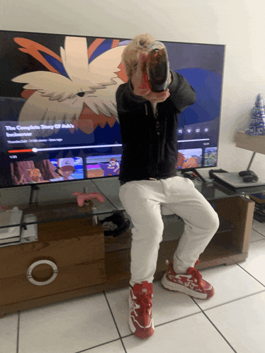a person sitting in front of a tv that says the complete story of ash on it