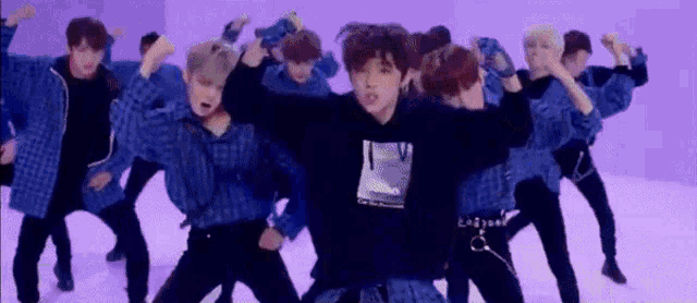 a group of young men are dancing in front of a purple wall .
