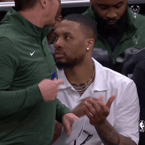 a man in a green nike jacket is talking to a basketball player