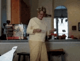 a woman in a yellow sweater is dancing in a room