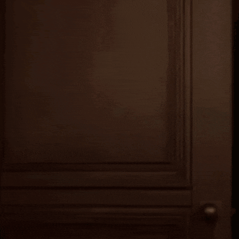 a dark room with a green wall and a door open