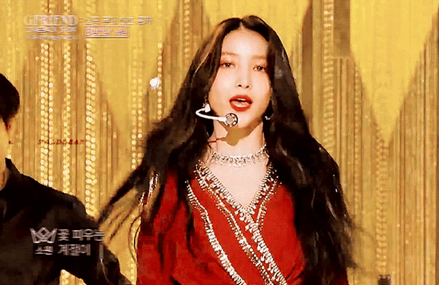 a woman in a red dress stands in front of a gold curtain with the words gfriend written on it