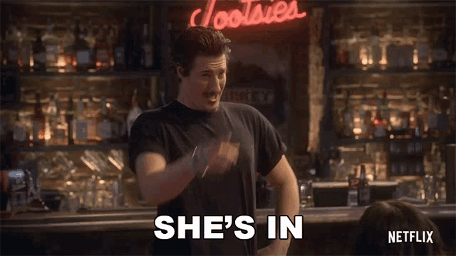a man in a bar says she 's in in front of a coors light sign