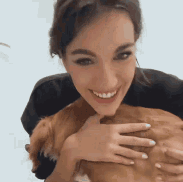 a woman is holding a brown dog and smiling for the camera
