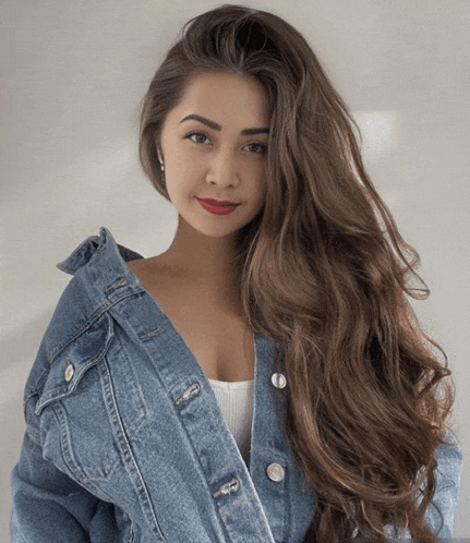 a woman with long brown hair is wearing a blue denim jacket