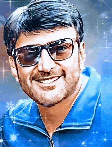 a man wearing sunglasses and a blue jacket smiles at the camera