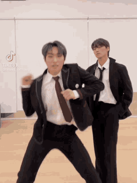 two men in suits and ties are dancing in front of a mirror