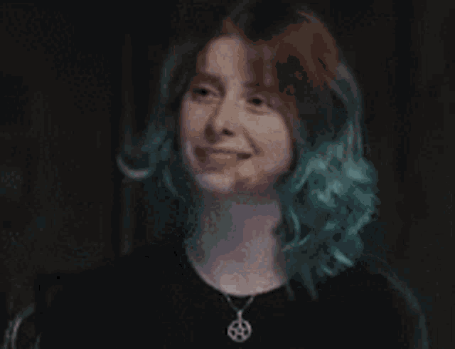 a woman with blue hair is screaming in a dark room while wearing headphones .