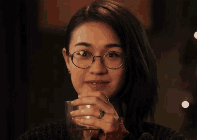 a woman wearing glasses is holding a glass of wine