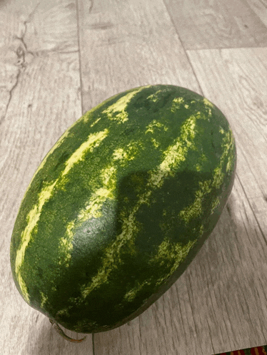 a watermelon is sitting on a wooden surface