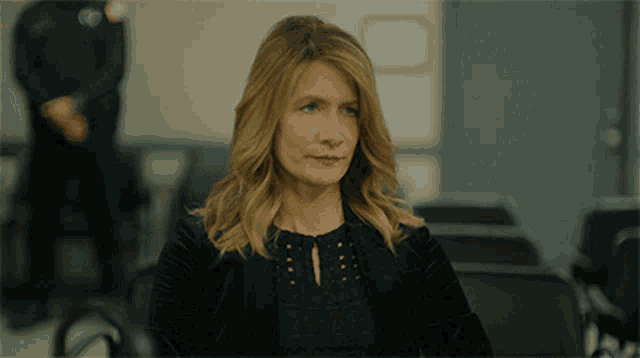 a woman in a black jacket sits in a waiting room