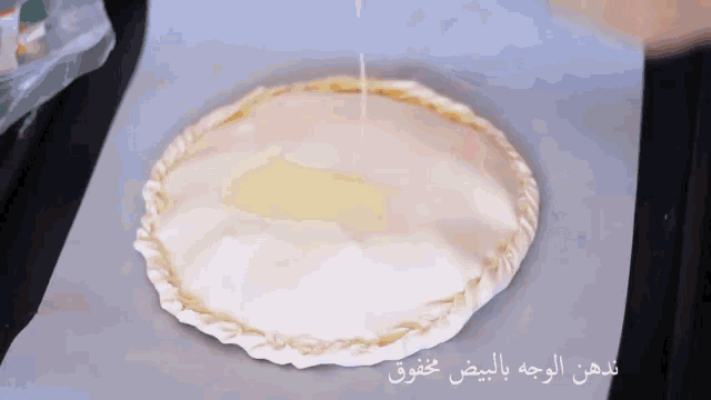 a pie with arabic writing on it is being poured with butter