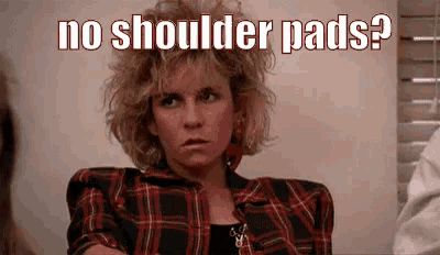 a woman in a plaid shirt is sitting in front of a window with the words `` no shoulder pads '' written above her .