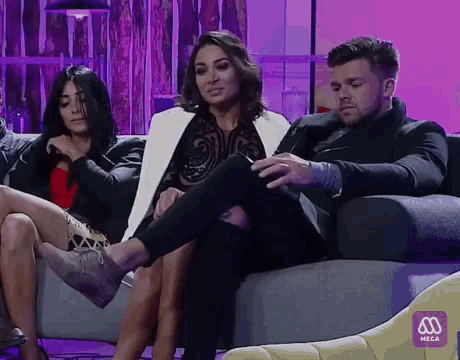 a group of people are sitting on a couch with a purple sign that says neza in the corner