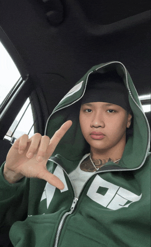 a man wearing a green hoodie with the letter o on it