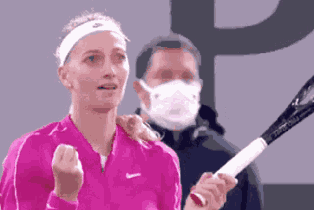a woman in a pink nike shirt is holding a tennis racket