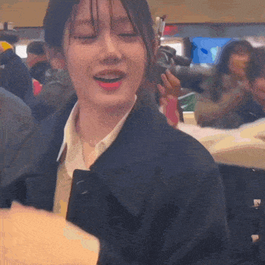 a woman in a black coat is smiling in a crowded room