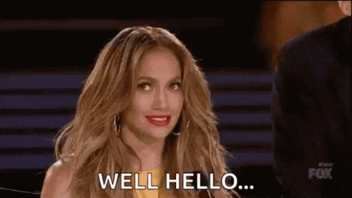 a woman is sitting in front of a man and says `` well hello '' .