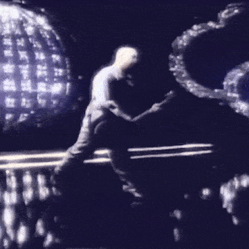 a woman in a black dress is dancing on a stage in front of a crowd .