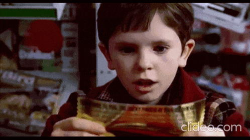 a young boy is looking at a chocolate bar in a store